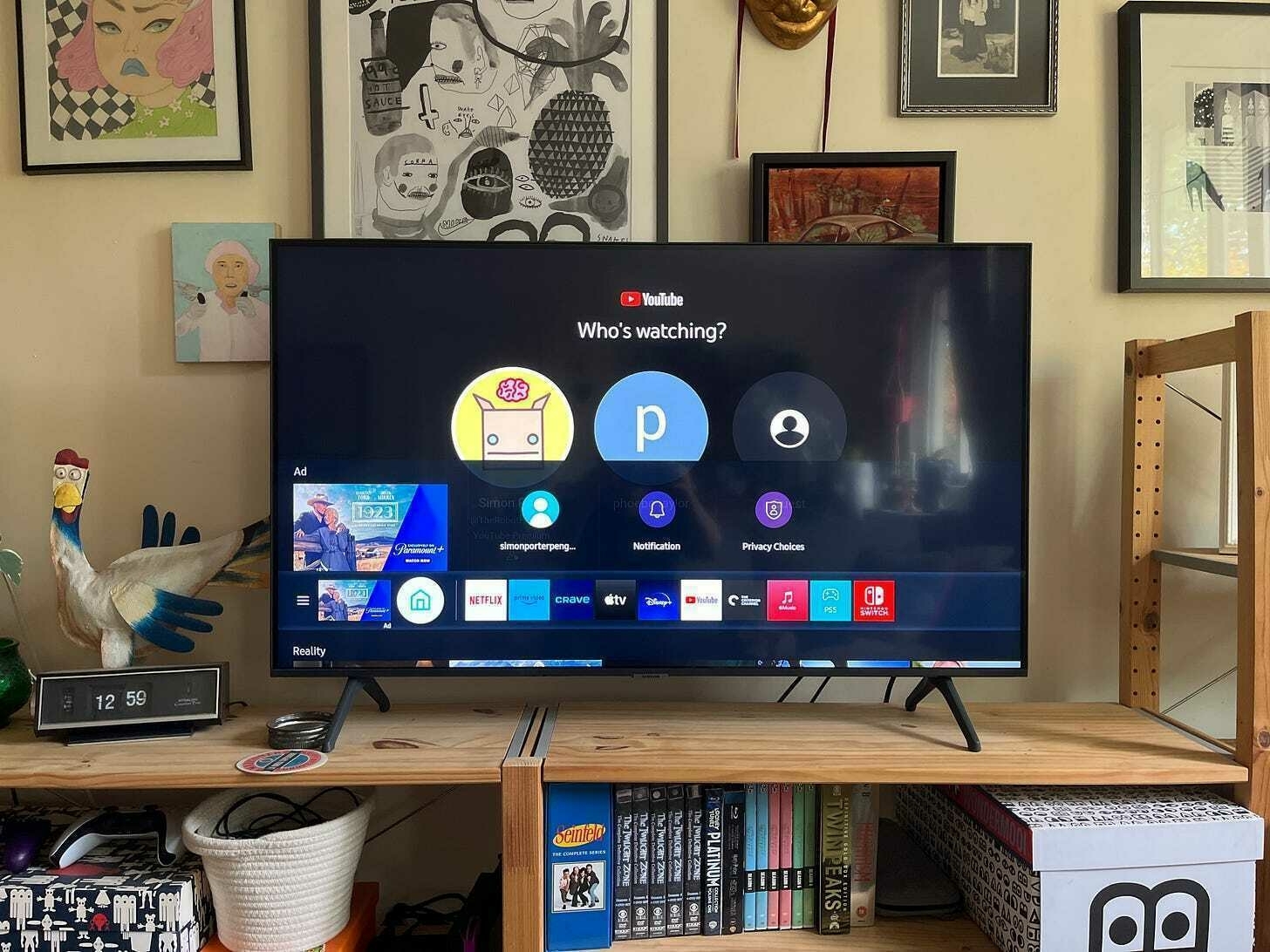 Photo of a TV with the main menu open at the bottom of the screen. It shows a row of icons along the bottom of the screen, but they are raised slightly from the bottom edge by a sliver of another interface. The tops of five video thumbnails poke in from the bottom along with the heading "Reality"