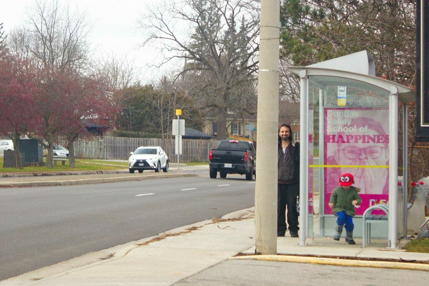 Another ad, "Dundas Valley School of Happiness" shows an excited person. This photo has a kid playing in front of the ad.